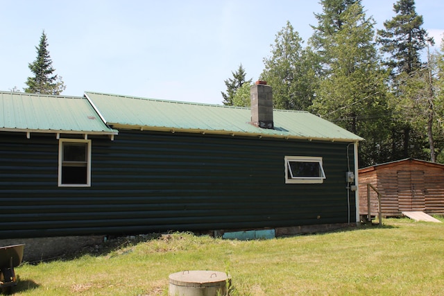189 E Shore Rd, Benedicta Twp, ME 04733 - view of home's exterior with a lawn, a storage shed, a metal roof, and a chimney