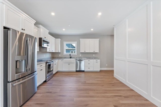 50 Ocean Park Rd Unit 102, Saco, ME 04072 - kitchen featuring appliances with stainless steel finishes, white cabinetry, light stone counters, recessed lighting, and light wood finished floors