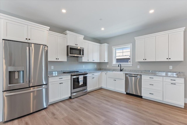 50 Ocean Park Rd Unit 102, Saco, ME 04072 - kitchen with stainless steel appliances, white cabinets, light stone counters, light wood-style flooring, and recessed lighting