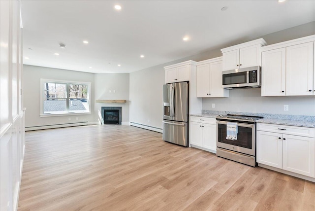 50 Ocean Park Rd Unit 102, Saco, ME 04072 - kitchen with appliances with stainless steel finishes, a baseboard heating unit, a baseboard radiator, light wood-style flooring, and white cabinetry