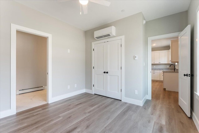 50 Ocean Park Rd Unit 102, Saco, ME 04072 - unfurnished bedroom featuring a baseboard heating unit, a wall unit AC, light wood-style flooring, a closet, and a ceiling fan