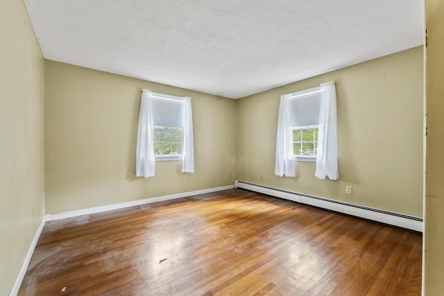 28 Colony Rd, Augusta, ME 04330 - empty room featuring baseboard heating, healthy amount of natural light, wood finished floors, and a textured ceiling