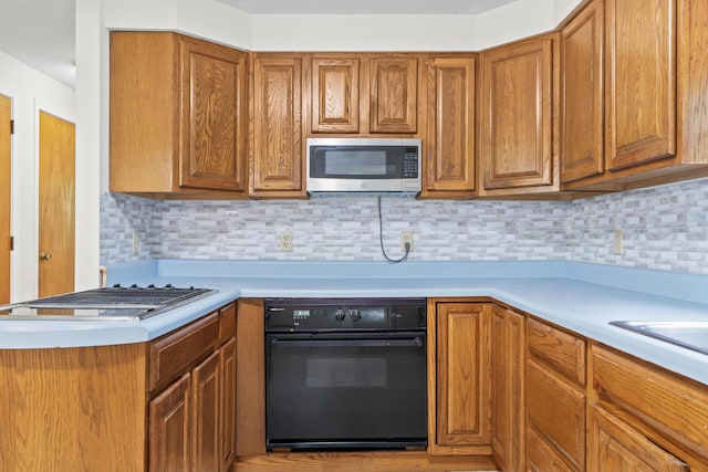 28 Colony Rd, Augusta, ME 04330 - kitchen with stainless steel microwave, light countertops, brown cabinets, and tasteful backsplash