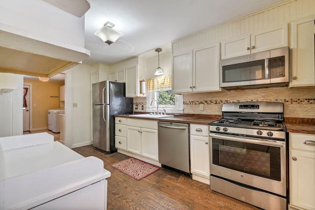 212 Lincoln St, Bangor, ME 04401 - kitchen with stainless steel appliances, separate washer and dryer, dark wood finished floors, decorative backsplash, and hanging light fixtures