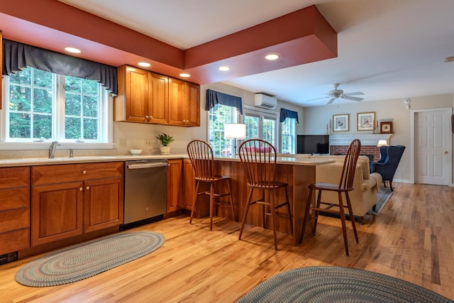 51 Tracy Cove Cir, Rome, ME 04963 - kitchen featuring stainless steel dishwasher, a wall unit AC, brown cabinetry, light wood finished floors, and recessed lighting
