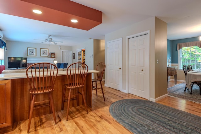 51 Tracy Cove Cir, Rome, ME 04963 - kitchen featuring light wood-style floors, brown cabinets, a kitchen breakfast bar, ceiling fan, and open floor plan