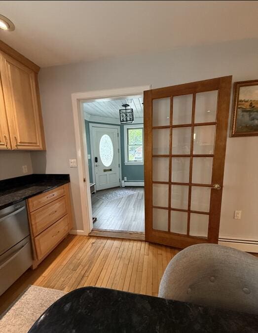 45 Tyler Ave, Bangor, ME 04401 - kitchen with stainless steel dishwasher, light wood-type flooring, baseboard heating, dark countertops, and light brown cabinetry