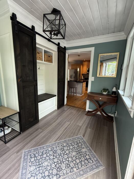 45 Tyler Ave, Bangor, ME 04401 - mudroom with a barn door, light wood finished floors, and ornamental molding