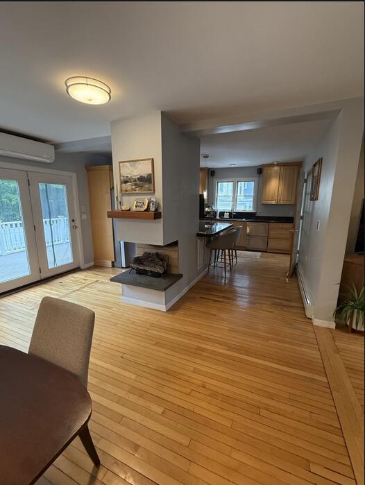 45 Tyler Ave, Bangor, ME 04401 - living room with a wall mounted AC, light wood finished floors, a multi sided fireplace, french doors, and baseboard heating