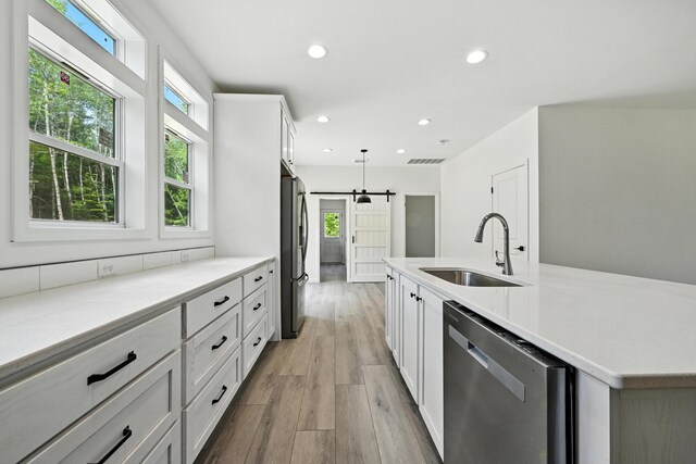 4 Willis Rd, Benton, ME 04901 - kitchen with appliances with stainless steel finishes, a barn door, light wood-style floors, recessed lighting, and white cabinetry