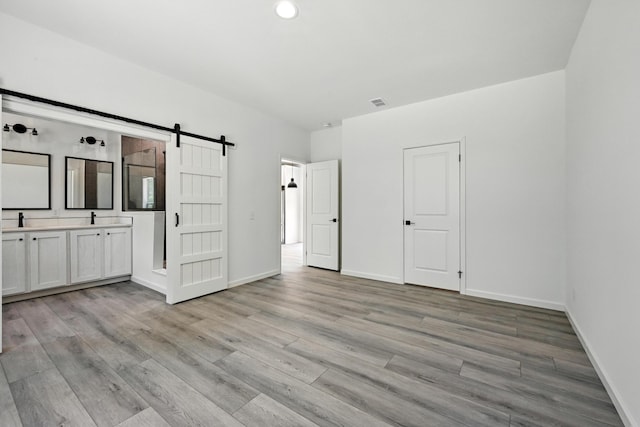 4 Willis Rd, Benton, ME 04901 - unfurnished bedroom featuring a barn door, light wood-type flooring, recessed lighting, and ensuite bathroom