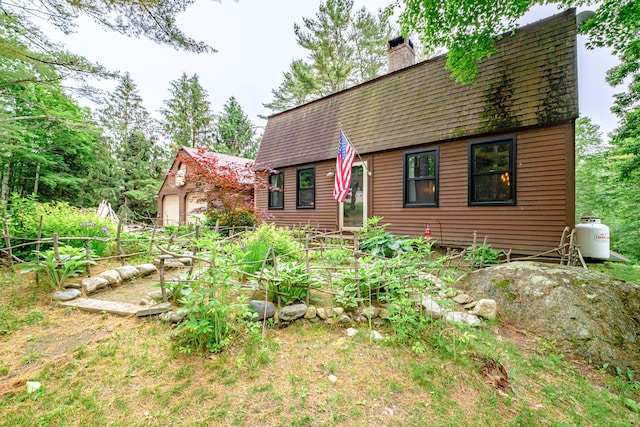 860 Gardiner Rd, Wiscasset, ME 04578 - view of front of house featuring a garden, a shingled roof, a chimney, and a garage