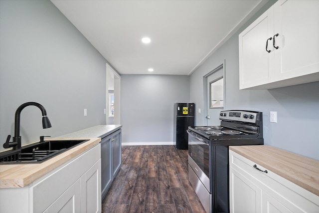 159 N St, Calais, ME 04619 - kitchen with stainless steel electric range, butcher block counters, dark wood finished floors, freestanding refrigerator, and white cabinetry