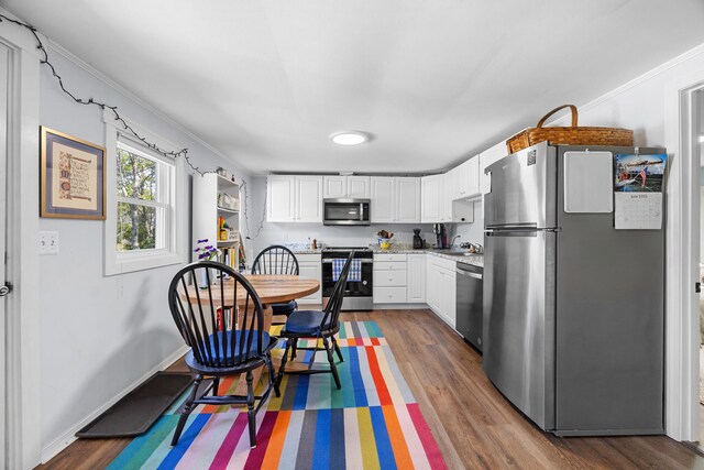 1165 Castine Rd, Penobscot, ME 04476 - kitchen featuring stainless steel appliances, dark wood finished floors, white cabinetry, light countertops, and ornamental molding