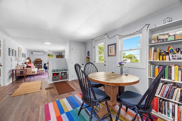 1165 Castine Rd, Penobscot, ME 04476 - dining space with a wall mounted AC, wood finished floors, and crown molding