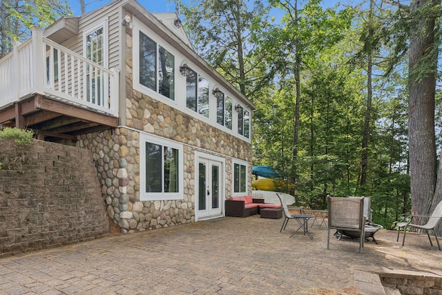 115 34th St, Acton, ME 04001 - rear view of house featuring stone siding, french doors, a patio, and an outdoor living space with a fire pit
