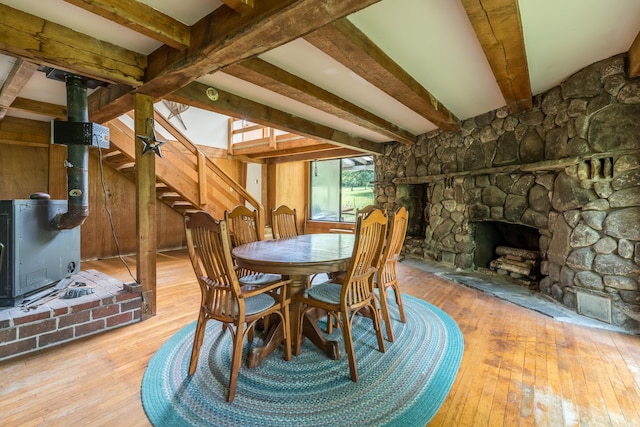115 Swain Farm Rd, Rumford, ME 04276 - dining room featuring a wood stove, wood-type flooring, beam ceiling, a fireplace, and stairs