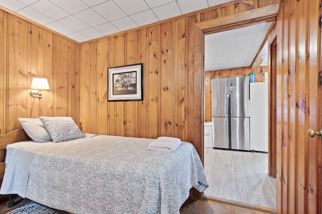 60 Butterworth Dr Unit 40, 46, Naples, ME 04055 - bedroom with freestanding refrigerator, wooden walls, and light wood-style flooring