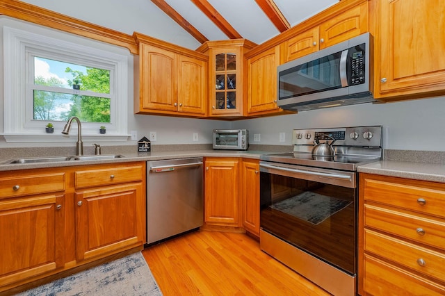 15 Vine St Unit B, South Berwick, ME 03908 - kitchen featuring appliances with stainless steel finishes, light wood-style floors, light countertops, glass insert cabinets, and brown cabinets