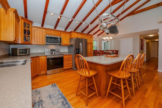 15 Vine St Unit B, South Berwick, ME 03908 - kitchen featuring stainless steel appliances, light wood-style floors, light countertops, glass insert cabinets, and a breakfast bar area