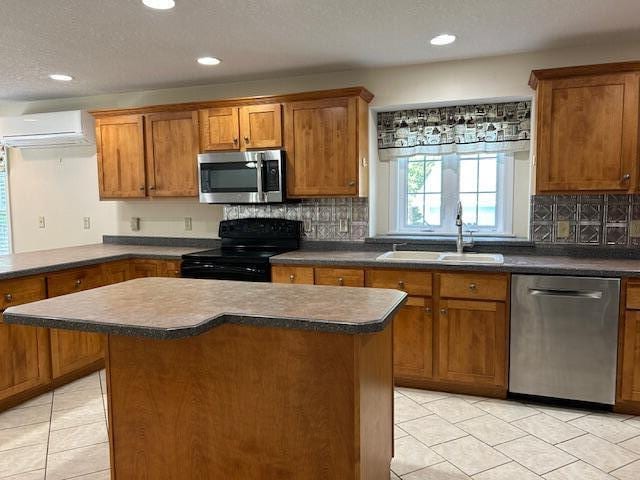 1 S Ridge Dr, Winslow, ME 04901 - kitchen with stainless steel appliances, a wall mounted AC, dark countertops, light tile patterned floors, and brown cabinetry
