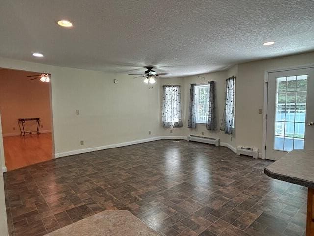 1 S Ridge Dr, Winslow, ME 04901 - unfurnished living room with a ceiling fan, a baseboard radiator, healthy amount of natural light, recessed lighting, and a textured ceiling