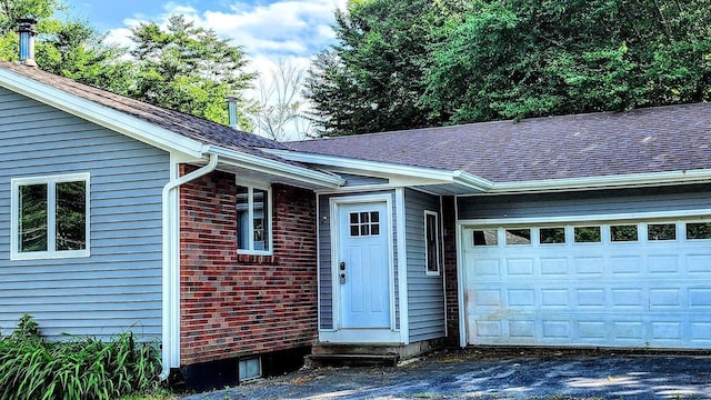 30 Grand Ave, Millinocket, ME 04462 - property entrance featuring an attached garage, roof with shingles, asphalt driveway, and brick siding