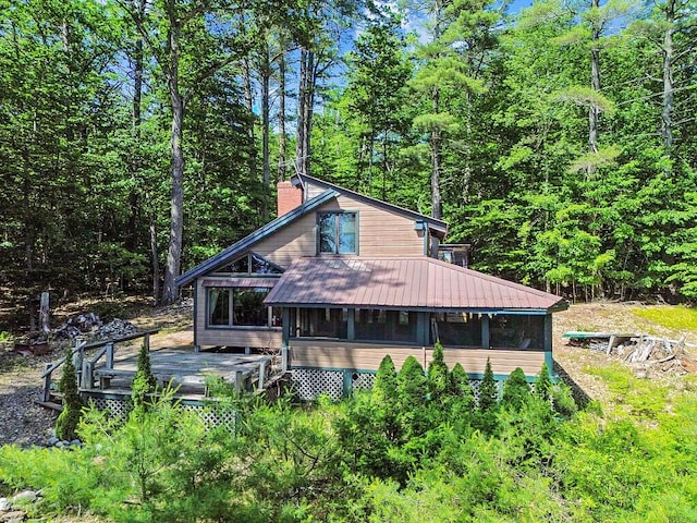 8 Horseshoe Is, Winthrop, ME 04364 - view of property exterior featuring a sunroom, a chimney, a deck, a wooded view, and a metal roof