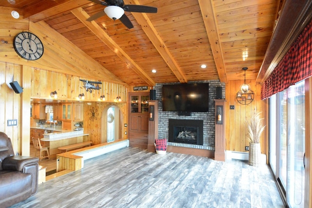 13 S Brook Ln, Eagle Lake, ME 04739 - unfurnished living room with wood finished floors, wooden walls, wooden ceiling, ceiling fan, and a brick fireplace