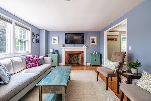 325 Ludlow St, Portland, ME 04102 - living room with a wall mounted AC, healthy amount of natural light, light wood-type flooring, and a brick fireplace