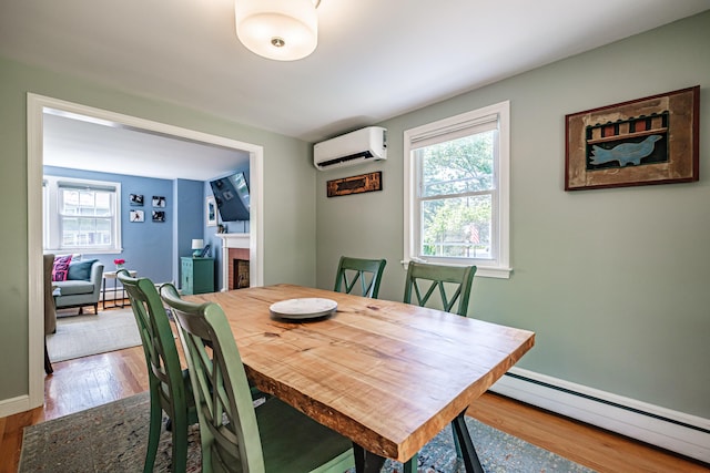 325 Ludlow St, Portland, ME 04102 - dining room featuring a baseboard heating unit, a wall unit AC, a fireplace, wood finished floors, and healthy amount of natural light