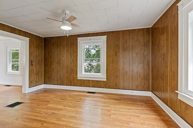 7 James St, Bingham, ME 04920 - spare room with plenty of natural light, light wood finished floors, ceiling fan, wood walls, and ornamental molding