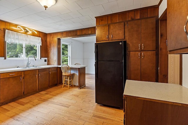7 James St, Bingham, ME 04920 - kitchen with freestanding refrigerator, light wood-style floors, light countertops, wood walls, and a peninsula