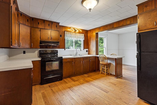 7 James St, Bingham, ME 04920 - kitchen featuring black appliances, under cabinet range hood, light wood-type flooring, and wooden walls