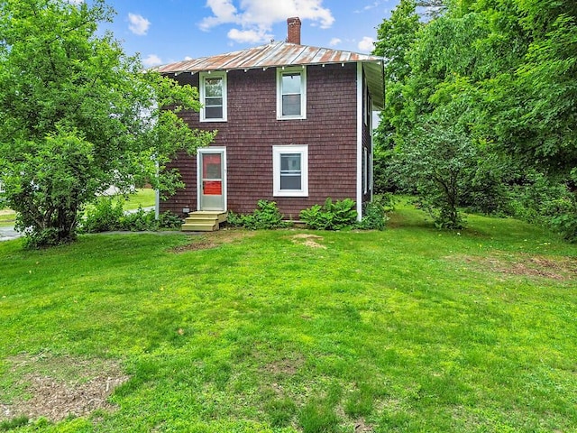 7 James St, Bingham, ME 04920 - view of front facade featuring entry steps, a front yard, a metal roof, a standing seam roof, and a chimney