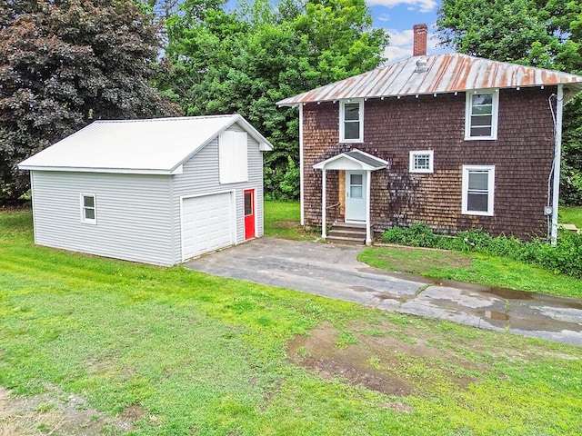 7 James St, Bingham, ME 04920 - view of front facade featuring an outdoor structure, a front lawn, a metal roof, a chimney, and a detached garage