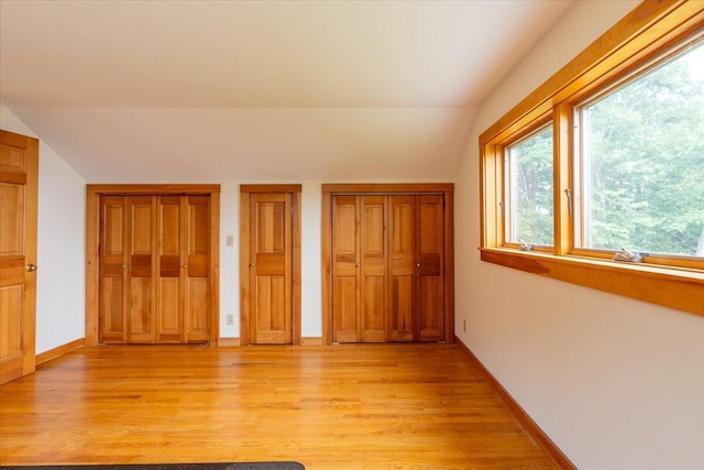 391 Main Rd, Islesboro, ME 04848 - unfurnished bedroom featuring vaulted ceiling, light wood-style flooring, multiple windows, and two closets