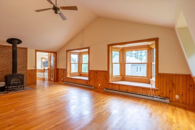 391 Main Rd, Islesboro, ME 04848 - unfurnished living room with baseboard heating, a wainscoted wall, a wood stove, wood finished floors, and vaulted ceiling