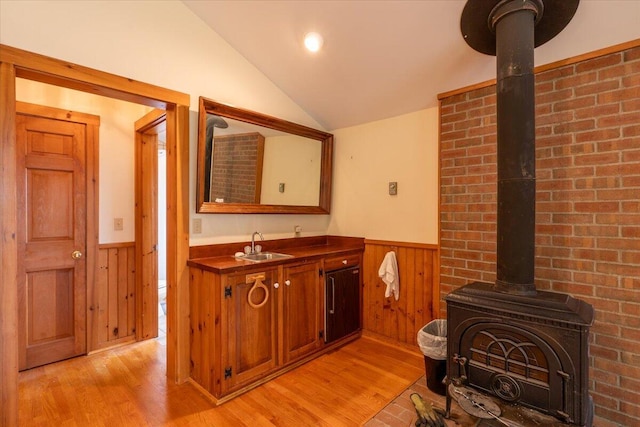 391 Main Rd, Islesboro, ME 04848 - bathroom with wainscoting, a wood stove, vaulted ceiling, wood finished floors, and vanity