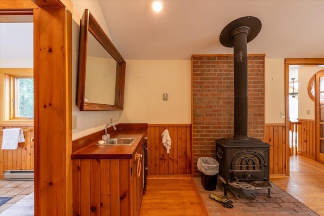 391 Main Rd, Islesboro, ME 04848 - bathroom with baseboard heating, a wainscoted wall, a wood stove, wooden walls, and wood finished floors