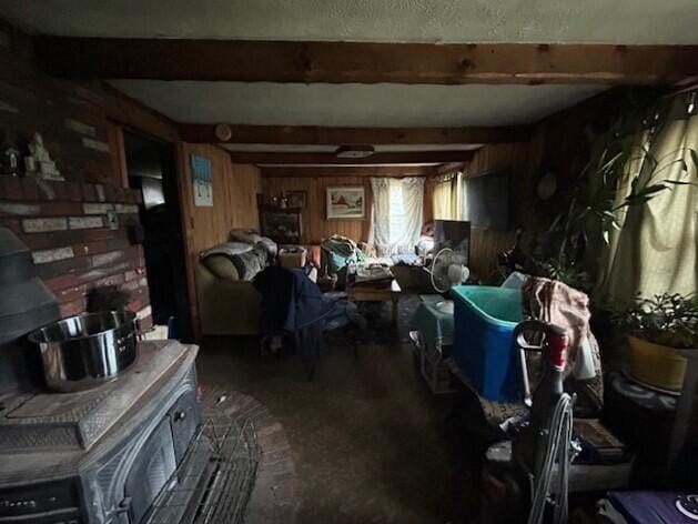 258 Guinea Rd, Biddeford, ME 04005 - living room featuring a wood stove, wood walls, and beam ceiling