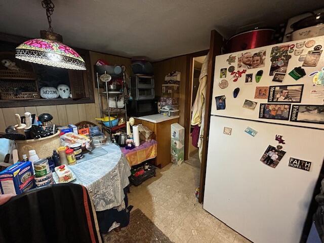 258 Guinea Rd, Biddeford, ME 04005 - kitchen featuring freestanding refrigerator, wooden walls, and black microwave