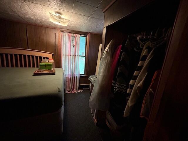 258 Guinea Rd, Biddeford, ME 04005 - bedroom with dark carpet and wood walls