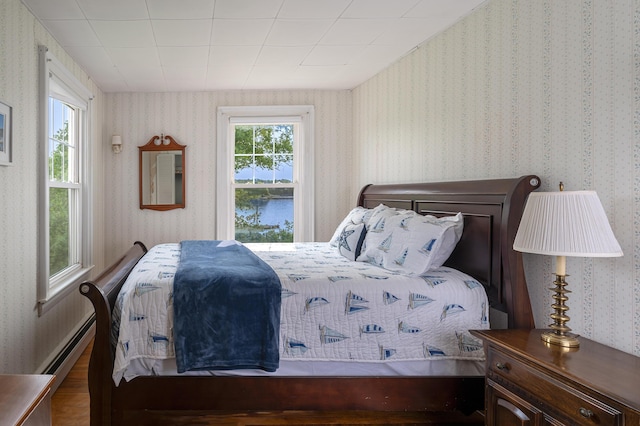 122 Isle Of Springs Rd, Boothbay, ME 04537 - bedroom with wallpapered walls, a water view, a baseboard radiator, and wood finished floors