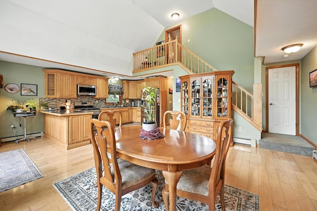 146 Lone Indian Trl, Augusta, ME 04330 - dining area featuring a baseboard radiator, light wood finished floors, high vaulted ceiling, and stairs