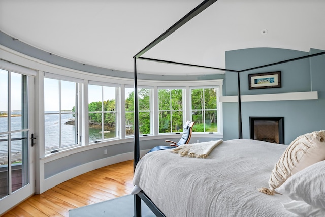 10 Cromwell Cove Rd, Harpswell, ME 04079 - bedroom with a water view, wood finished floors, multiple windows, and a fireplace