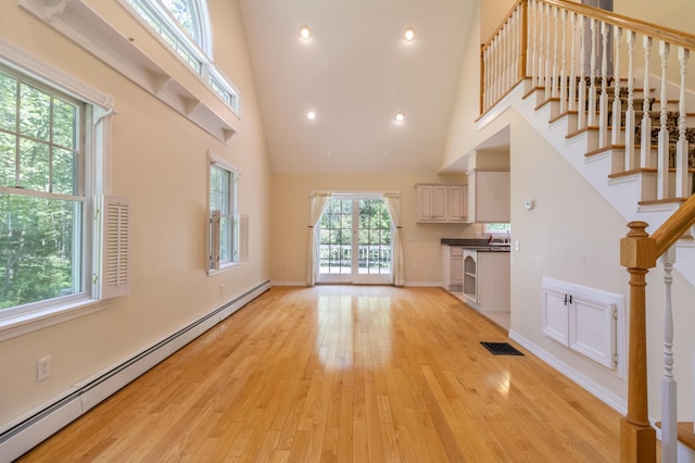 26 Spruce St, Bucksport, ME 04416 - unfurnished living room featuring baseboard heating, a high ceiling, stairs, light wood-style flooring, and recessed lighting