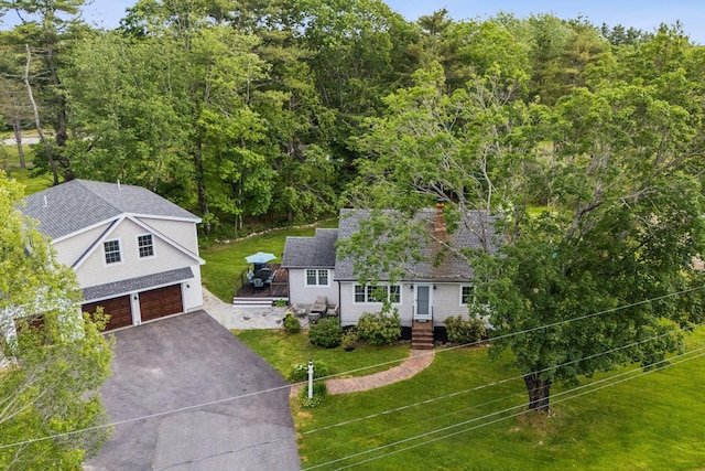 10 Burnell Dr, Yarmouth, ME 04096 - view of front of property with a garage, asphalt driveway, a front yard, a shingled roof, and a forest view