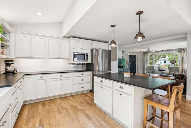 10 Burnell Dr, Yarmouth, ME 04096 - kitchen with stainless steel appliances, dark countertops, tasteful backsplash, a kitchen breakfast bar, and light wood-style flooring