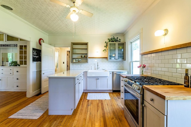 21 Elm St, Belfast, ME 04915 - kitchen with stainless steel appliances, open shelves, light wood finished floors, ceiling fan, and a peninsula